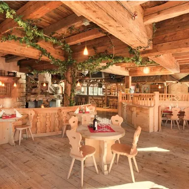 Ein gemütliches Restaurant mit Holzmöbeln und warmem Licht. Pflanzen und Holzverzierungen schaffen eine einladende Atmosphäre.