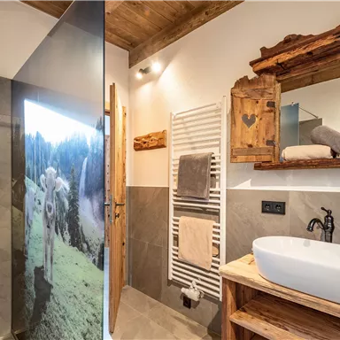 Ein modernes Badezimmer mit einer Dusche und einem Holzwaschtisch. Eine helle Atmosphäre durch natürliche Materialien und eine stilvolle Gestaltung.