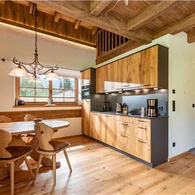 Eine moderne Küche mit Holzschränken und einer gemütlichen Essecke. Das helle, einladende Design schafft eine warme Atmosphäre.