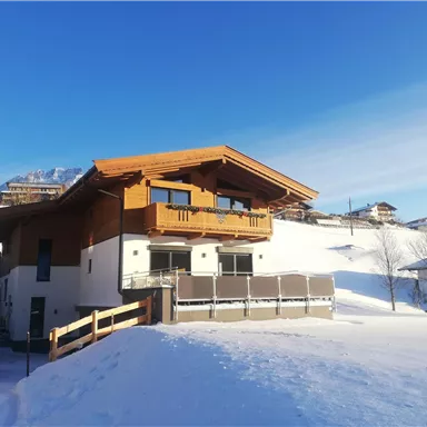 Ein modernes Holzhaus in verschneiter Landschaft. Der klare blaue Himmel sorgt für ein schönes Winterambiente.