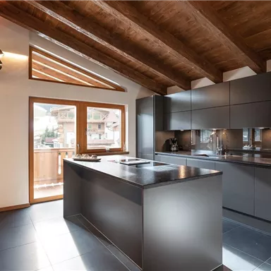 Moderne Küche mit Holzdecken und viel natürlichem Licht. Dezenete, elegante Möbel und große Fenster bieten eine schöne Aussicht.