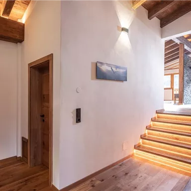 Ein einladender Flur mit Holzdecke und einem hellen Treppenaufgang. Es gibt große Fenster, die viel Licht hereinlassen.