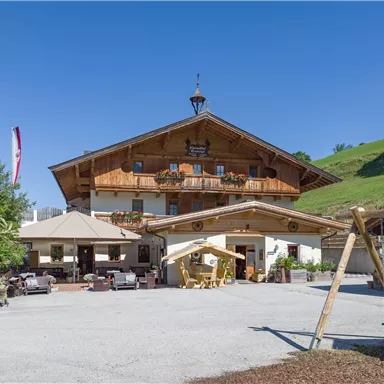 Ein traditionelles Holzhaus in den Alpen mit einem gepflegten Außenbereich. Die Umgebung ist grün und lädt zum Entspannen ein.