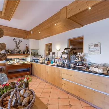 Ein einladender Verkaufsraum mit Holzregalen und Auslagen. Es gibt verschiedene handgefertigte Produkte und eine gemütliche Atmosphäre.