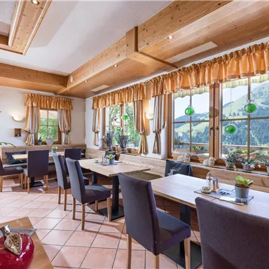 Ein einladendes Restaurant mit großen Fenstern und Blick auf die Natur. Die Einrichtung ist gemütlich und modern, mit Holzdetails und eleganten Stühlen.