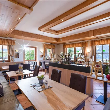 Ein helles und einladendes Restaurant mit holzverkleideten Wänden. Die Tische sind sorgfältig gedeckt und große Fenster sorgen für viel Licht.