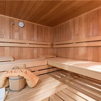 Eine Sauna mit Holzregalen und einem Eimer. Die Atmosphäre ist warm und einladend.
