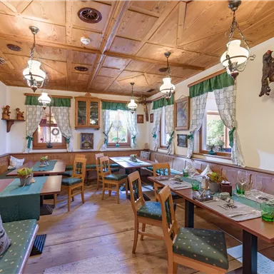 Ein gemütliches Restaurant mit traditioneller Holzdeko und warmem Ambiente. Die Tische sind freundlich gedeckt, und die Wände sind mit rustikalen Bildern geschmückt.