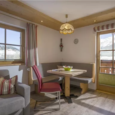 Cozy living area with a dining table and bench. Large windows provide a view of the mountains and ensure plenty of daylight.