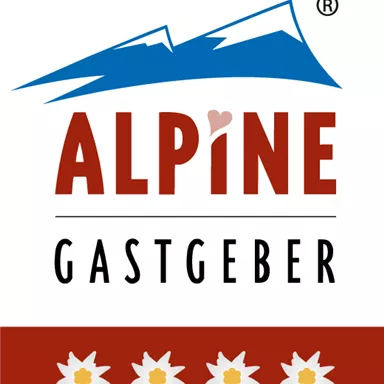 A logo with the inscription "ALPINE GASTGEBER" and stylized mountains. The colors are red, blue, and white, with Edelweiss flowers at the bottom.