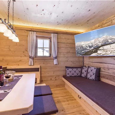 A cozy room with wooden walls and a large television. A table with wine and glasses invites you to linger.
