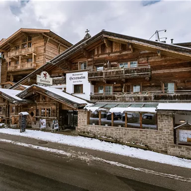 Ein traditionelle Holzarchitektur in den Bergen, umgeben von Schnee. Das Gebäude beherbergt ein Restaurant mit einer gemütlichen Atmosphäre.
