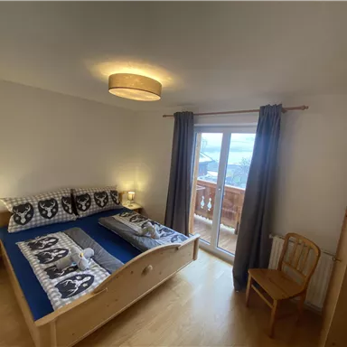 A cozy bedroom with two beds and modern bed linens. The large window front offers a beautiful view outside.