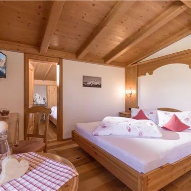 Ein gemütliches Schlafzimmer mit Holzmöbeln und einem großen Bett. Die Wände sind hell und es gibt ein Fenster, das natürliches Licht hereinlässt.