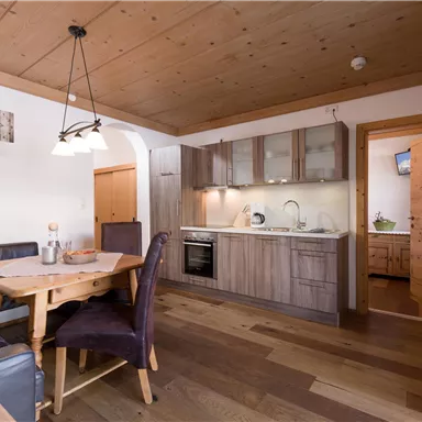 Eine gemütliche Küche mit Essbereich und modernen Geräten. Der Raum hat Holzverkleidung und helle Farben, die eine einladende Atmosphäre schaffen.