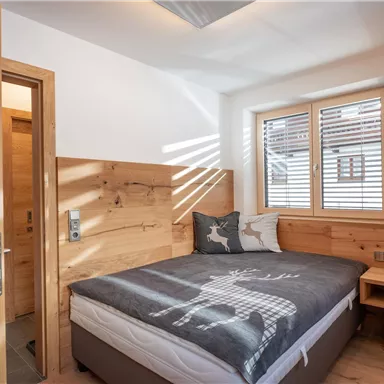 Ein gemütliches Schlafzimmer mit Holzverkleidung und einem großen Bett. Das Zimmer hat viel natürliches Licht und eine moderne, einladende Atmosphäre.