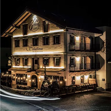 A stylish restaurant building at night, brightly lit. It has a charming, traditional style with large windows and an inviting atmosphere.