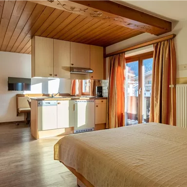 A cozy room with a double bed and an open kitchenette. Large windows provide plenty of natural light and a beautiful view.