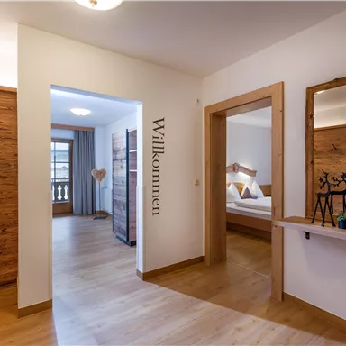 A bright entrance area with wooden paneling and a large mirror. The word "Welcome" is visible on the wall.