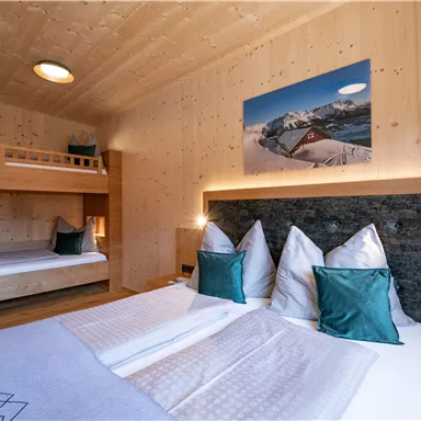 Ein gemütliches Schlafzimmer mit Holzverkleidung und zwei Betten. Die Wände sind mit einem Bild der Berge dekoriert.
