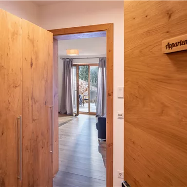 An inviting hallway with wooden panels that leads to a cozy apartment. A sign reads "Apartment Hans".