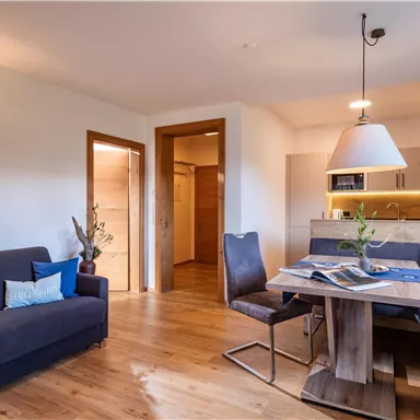 A modern living room with a cozy couch and a dining table. The bright, inviting atmosphere is highlighted by the wood design and the lighting.
