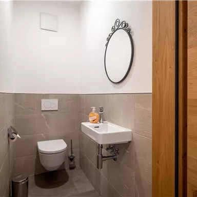 A modern small bathroom with a bright wall and an elegant mirror. The sanitary facilities are simple and functional.