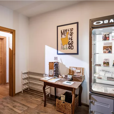 An inviting room with wooden walls and a table. A display case showcases products and magazines, while a piece of art hangs on the wall.