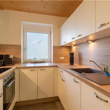 A modern kitchen with bright cabinets and wooden accents. The window lets in plenty of light and creates an inviting atmosphere.