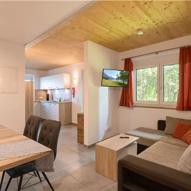 A modern apartment with an open living kitchen and a cozy living area. Bright walls and large windows create an inviting atmosphere.