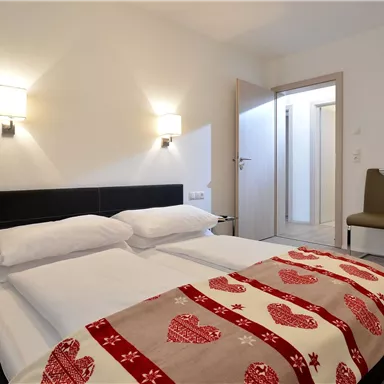 Ein gemütliches Schlafzimmer mit einem Doppelbett und einem modernen Design. Das Zimmer ist hell beleuchtet und hat einen Zugang zu einem Badezimmer.
