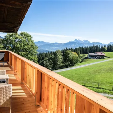 A beautiful balcony with a view of the mountains and the green landscape. The sun is shining and the sky is clear.
