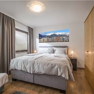 Ein modernes Schlafzimmer mit einem Doppelbett und einem großen Kleiderschrank. Die Wände sind neutral gehalten, und der Raum hat ein angenehmes, luftiges Gefühl.