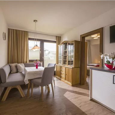 Ein gemütlicher Essbereich mit einem Tisch, Stühlen und einer Kommode. Das Licht strömt durch das Fenster und schafft eine einladende Atmosphäre.