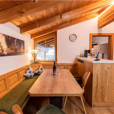 Eine gemütliche Wohnung mit Holzdecken und einem Esstisch aus Holz. Die Küche ist modern und gut ausgestattet.