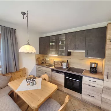 Eine moderne Küche mit Holzschränken und einem Esstisch. Die Räume sind hell und freundlich gestaltet.