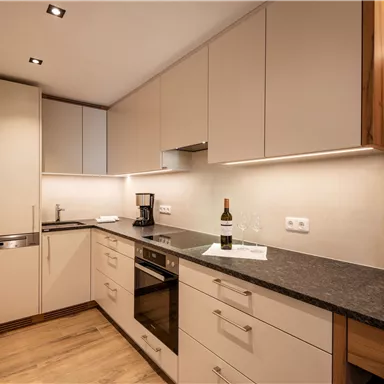 A modern kitchen with bright cabinets and a dark countertop. It is well-equipped and has a cozy atmosphere.