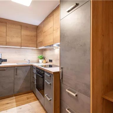 Eine moderne Küche mit Holz- und Betonelementen. Die Geräte sind funktional und der Raum wirkt einladend.