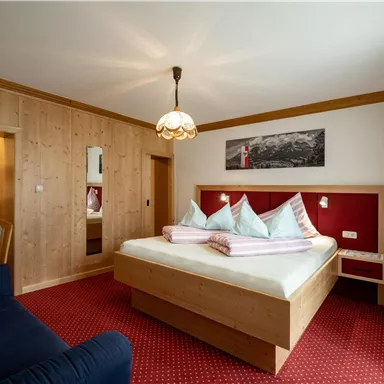 Ein gemütliches Schlafzimmer mit einem großen Bett und mehreren Kissen. Die Wände sind aus Holz und der Boden ist mit Teppich ausgelegt.