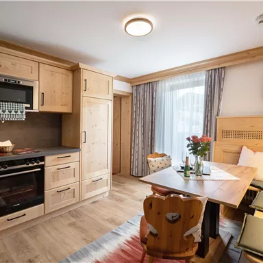 Eine gemütliche Küche mit modernen Annehmlichkeiten und natürlichem Holzinterieur. Der Esstisch lädt zum Verweilen ein und ist mit frischen Blumen dekoriert.