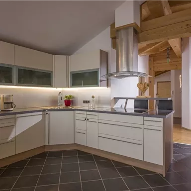 Eine moderne Küche mit hellen Schränken und schwarzen Arbeitsflächen. Sie verfügt über eine zentrale Kochinsel und hat eine gemütliche Atmosphäre.