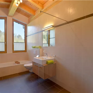 A modern bathroom with a window and a shower. It has bright tiles and wooden paneling for a cozy atmosphere.
