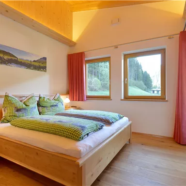 A cozy bedroom with wooden decor and two beds.
Large windows let in plenty of daylight and offer a view of nature.
