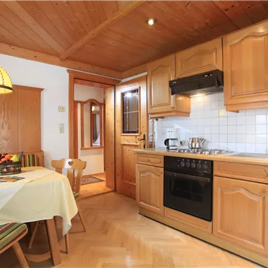 Eine gemütliche Küche mit Holzschränken und einem Esstisch. Die Einrichtung ist hell und einladend, mit einem typisch alpinen Flair.