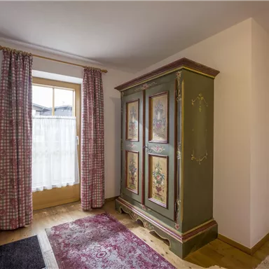 Ein einladender Eingangsbereich mit einem farbenfrohen Schrank und karierten Vorhängen. Der Raum ist hell und freundlich gestaltet.