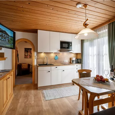 Eine gemütliche Küche mit Holzdecke und moderner Ausstattung. Der Tisch ist liebevoll gedeckt und ein großzügiges Fenster sorgt für viel Licht.