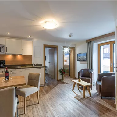 Eine gemütliche Wohnung mit modernen Möbeln und einer offenen Küche. Helle Räume mit großen Fenstern und Blick auf die Natur.