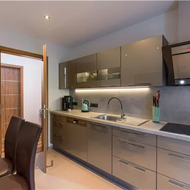 Moderne Küche mit glänzenden Schränken und einer eleganten Arbeitsfläche. Der Bereich ist gut beleuchtet und lädt zum Kochen ein.