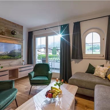 Ein gemütliches Wohnzimmer mit modernen Möbeln und einem großen Fenster. Das Zimmer ist hell und freundlich, mit einer schönen Aussicht nach draußen.