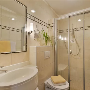 A modern bathroom with a shower cabin and a sink. The walls are painted in warm beige and brown tones.